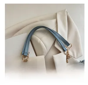 Détail macro de l'anse en cuir bleu clair et de l'élégante chaîne dorée sur sac en jean