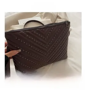 Macro detail of dark brown quilted leather envelope clutch with metallic rivet studs