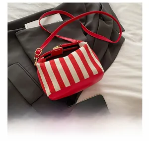 Detail view of red and white striped canvas crossbody bag with adjustable leather strap