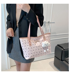 Detail of pink bow-patterned tote bag with metal bow buckle and cloud plush charm accessory