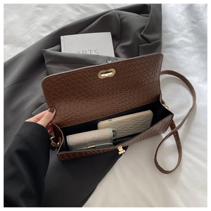 Detail view of brown woven crossbody bag with gold metal lock on soft fabrics