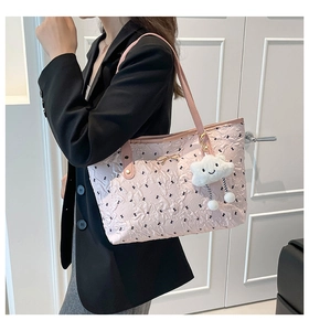 Pink tote bag detail with black bow embroidery and plush cloud charm on shoulder strap
