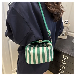 Rear view of a model wearing the green and white striped crossbody bag with leather strap