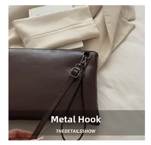 Detailed close-up of dark brown leather handbag with durable silver metal hardware hook
