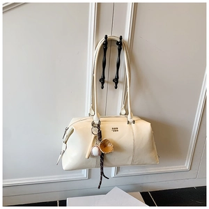 Detail of a creamy white Boston bag with a vintage metal logo and sports themed charms
