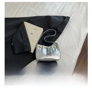 Detail show of silver metallic mini shoulder bag with gold drawstring ring and slim strap