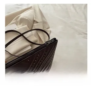 Detail of smooth silver zipper and decorative V-shaped studs on dark leather bag