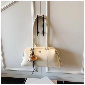 Detail of cream leather bowling bag with creative baseball glove charm and gold logo