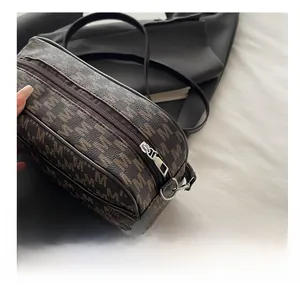 Close-up of smooth silver metal zipper and brown monogram pattern on a faux leather bag