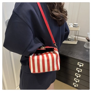 Detail of red and white striped crossbody canvas bag with adjustable leather shoulder strap