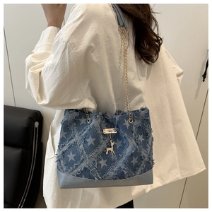 Detail view of denim tote bag featuring white star patterns and a gold deer charm