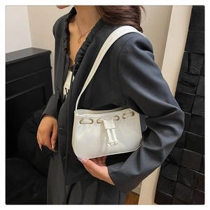 Detailed view of a white leather shoulder bag with drawstring detail and metal eyelets