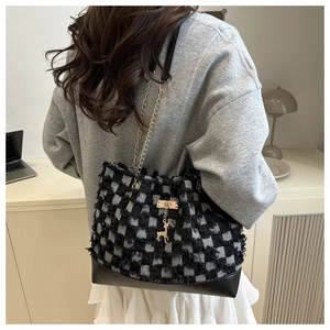 Détail du cabas en tweed à carreaux noir et blanc avec pendentif élan doré élégant