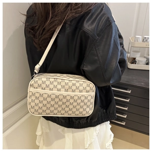 Detail of beige monogram crossbody bag with M-pattern and adjustable leather strap