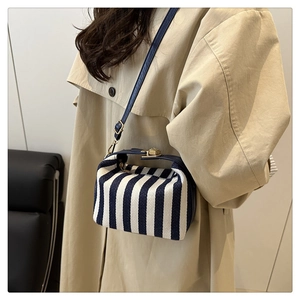 Detail einer gestreiften Mini-Tasche mit goldenen Beschlägen und blauen Lederriemen