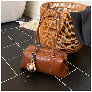 Detail view of brown leather bowling bag with vintage zipper and baseball glove charm