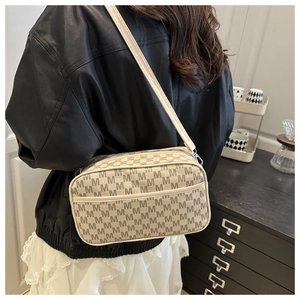 Detail view of cream crossbody bag featuring all-over dark grey letter M monogram patterns