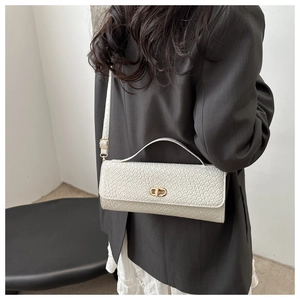 Detail of cream woven texture shoulder bag with gold metal clasp on a female model