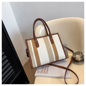 Detail of vintage striped tote bag with woven texture and brown faux leather straps