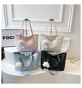 Close-up of textured tote bag with golden bow and cloud charm on display stand