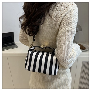 Detail of striped canvas handbag with gold hardware and adjustable crossbody strap
