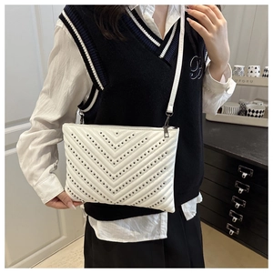 Detailed close-up of white chevron quilted handbag with dark metal rivets on strap
