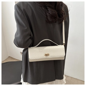 Detail of woven texture and golden clasp on off-white crossbody bag for women