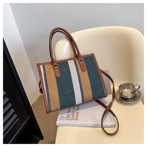 Detail of striped canvas tote with brown leather straps on a minimalist chair