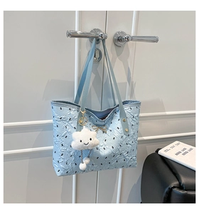 Detail of light blue pleated tote bag featuring black bow prints and cloud charm