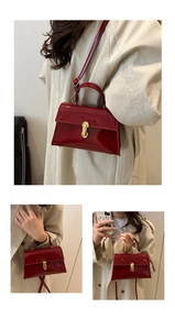Detail of red patent leather handbag with glossy finish and gold oval buckle hardware