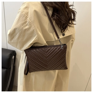 Detail of dark brown V-quilted shoulder bag with silver studs and metal zipper closure