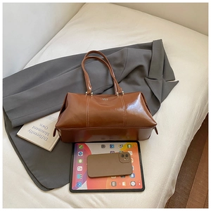 Flat lay of brown leather bowling bag showing spacious interior with tablet and phone
