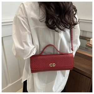 Detail of red square crossbody bag with faux crocodile pattern and gold oval twist lock