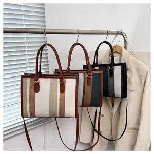 Detailed view of striped canvas tote bags in various colors on a display stand