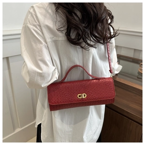 Detail of red croc-embossed leather handbag with gold twist lock and crossbody strap