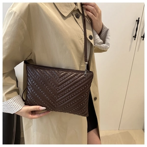 Detail view of coffee brown quilted crossbody bag with silver studs and zipper closure
