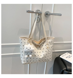 Close-up of white tote bag with black bow embroidery and gold hardware detail