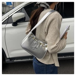 Detail of silver metallic underarm bag with gold eyelets and drawstring on a model