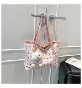 Detailed view of pink bubble textured tote bag with golden bow and white cloud charm