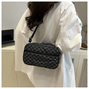 Detail of trendy crossbody bag featuring white M letter print and adjustable strap