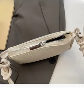 Close-up of silver zipper on cream lychee pattern leather bag with knotted strap detail