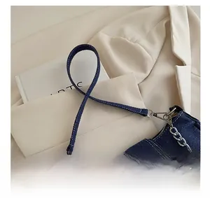 Detailaufnahme der dunkelblauen Denim-Schultertasche mit Metallschnalle und Kette
