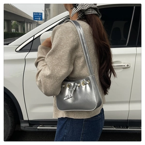 Detail of silver metallic underarm bag with drawstring closure in an outdoor setting