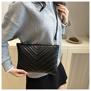 Detail of black quilted shoulder bag with silver studs in a chevron pattern