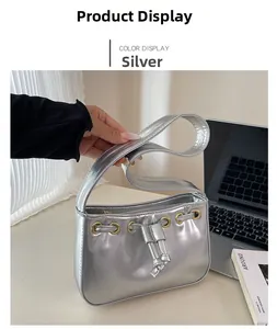 Close-up of silver metallic shoulder bag with gold eyelet details and drawstring on a desk