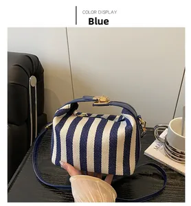 Detailaufnahme der blau-weiß gestreiften Canvas-Handtasche mit goldenem Drehverschluss