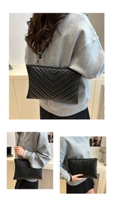 Close-up of black envelope bag with V-quilting, metallic studs and detachable strap