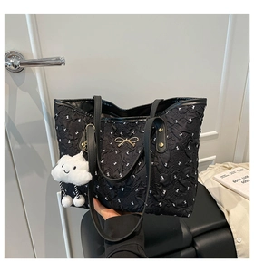 Close-up of black tote bag with white bunny prints and a golden bow decoration