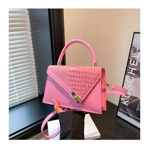 Sac à main rose effet croco avec rabat géométrique et fermoir doré dans un décor urbain chic