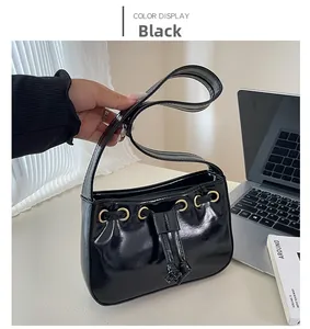 Detail of black glossy patent leather underarm bag with gold metal ring and handle